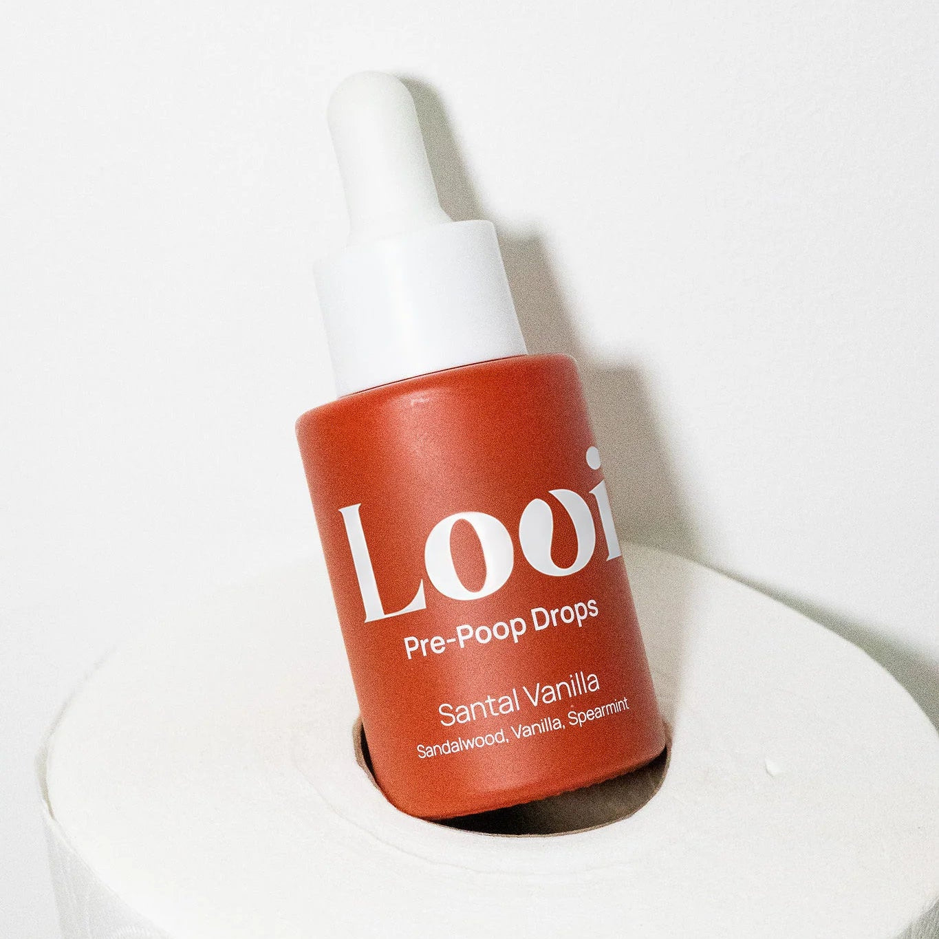 Bottle of Loui Pre-Poop Drops sitting on a roll of toilet paper with a white background