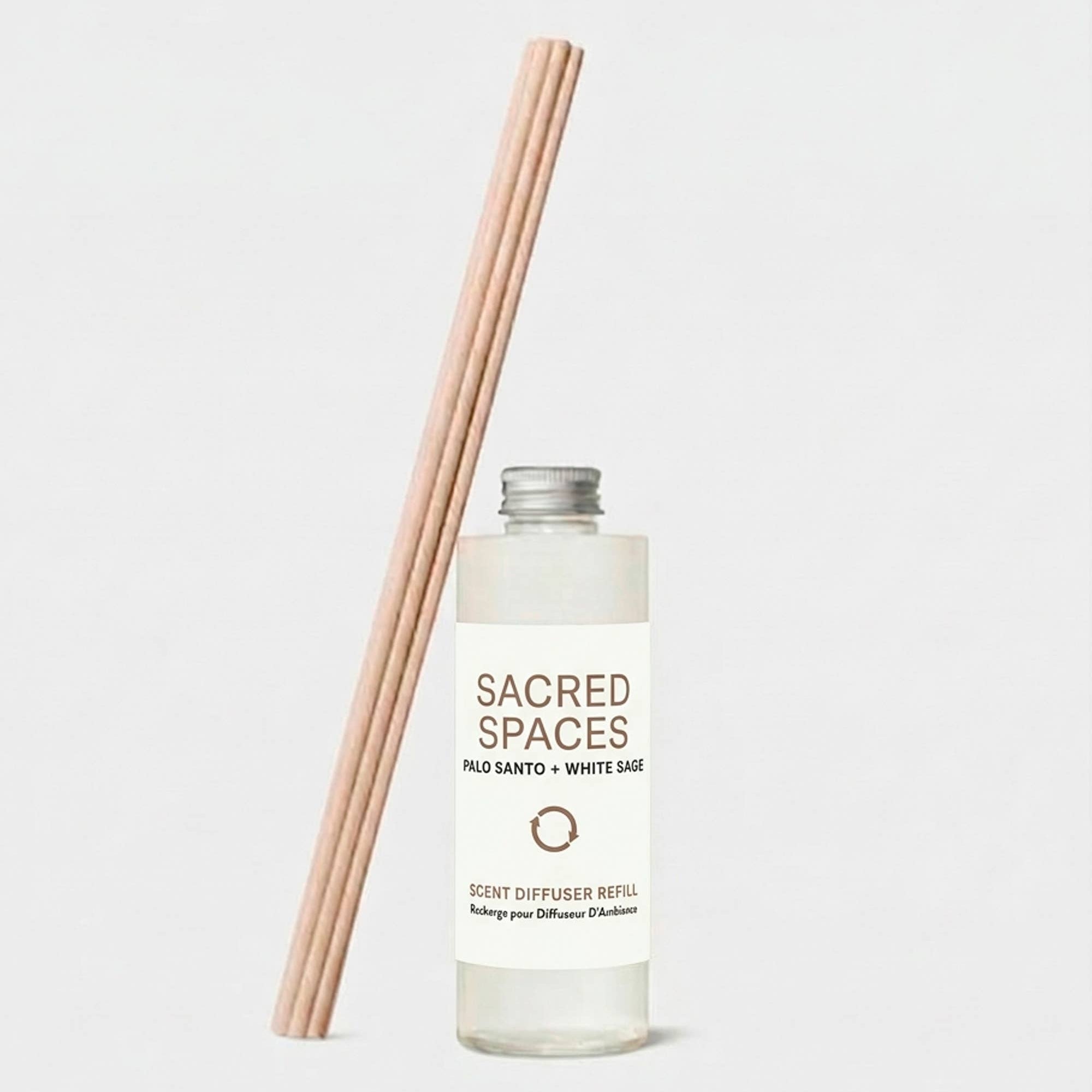 Sacred Spaces scent diffuser refill bottle with a bundle of reeds on a light gray background