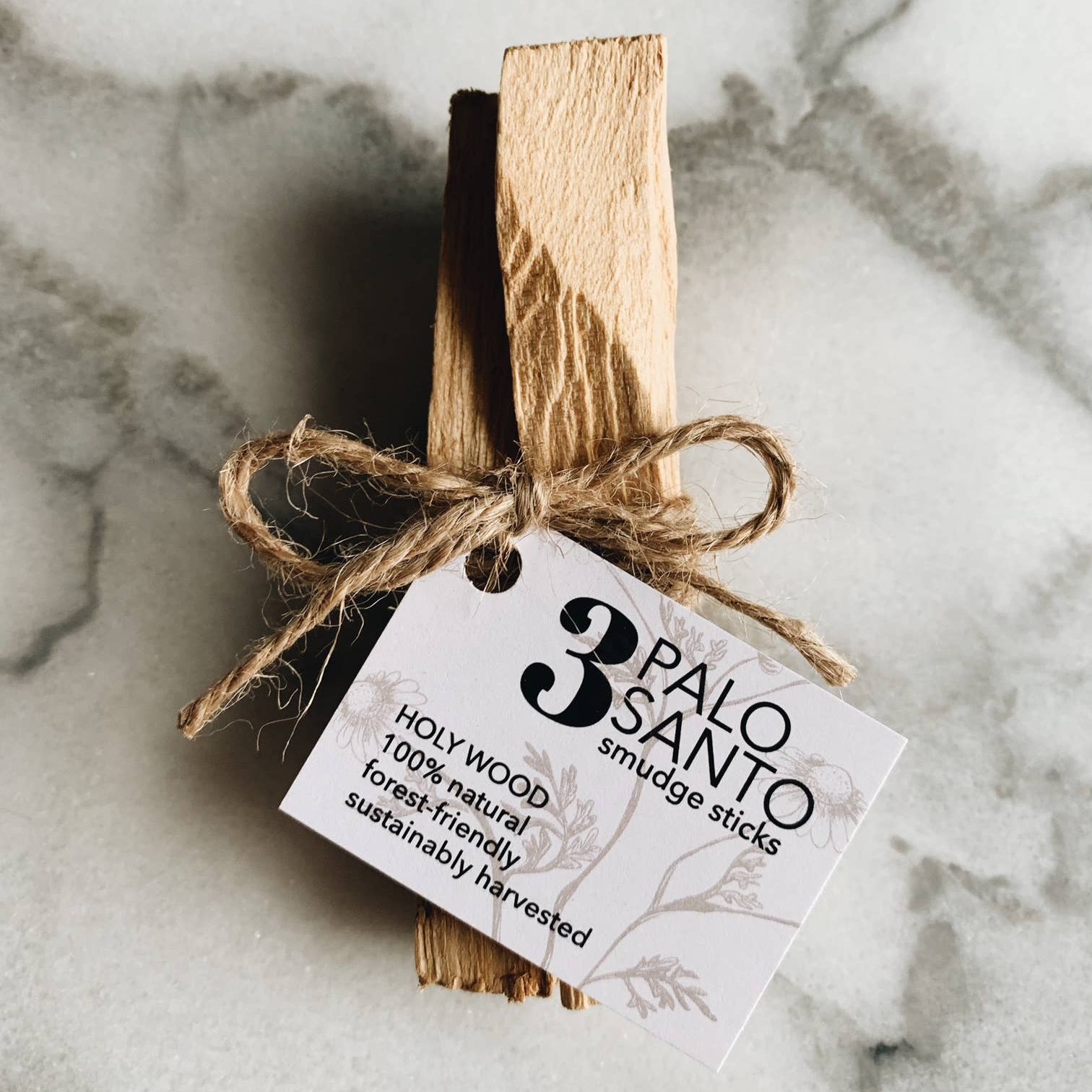 Palo Santo smudge sticks tied with twine on a marble surface